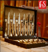 Elegant gold cutlery set neatly arranged in open black case with fnS Premium Dining branding.